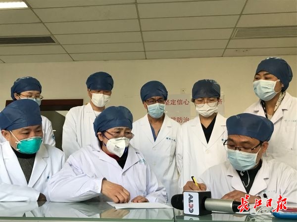 李兰娟院士（第一排中间）与武汉大学人民医院医生交流新的治疗方案。  记者黄琪 摄