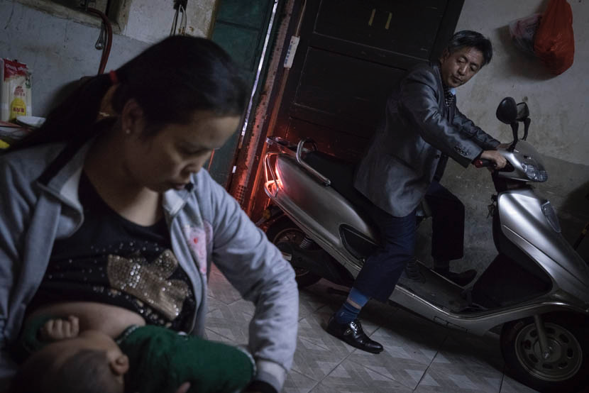 2015年3月，江西省凰岗镇，阿白的丈夫邹大哥（右）工作之后回到家，而阿白正在给他们的孩子喂奶。那时，邹大哥当摩托车手，每个月挣500美金。图/丛妍