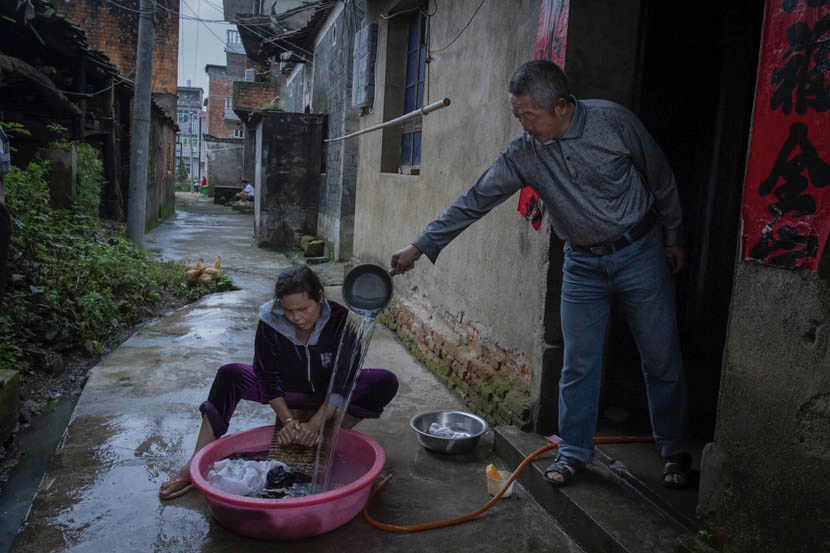 2015年6月，江西省凰岗镇，邹大哥（右）在阿白洗衣服时帮忙加水。图/丛妍