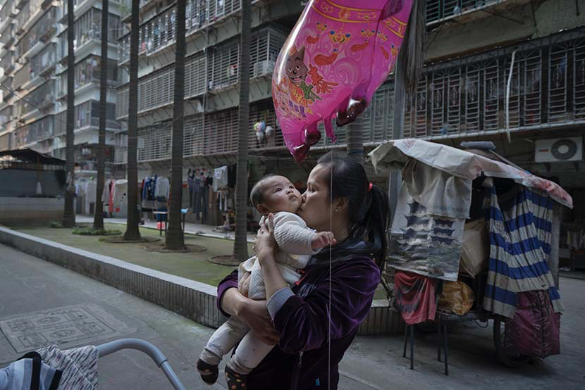 2015年3月，江西省凰岗镇，阿白在住宅楼前抱着孩子。图/丛妍