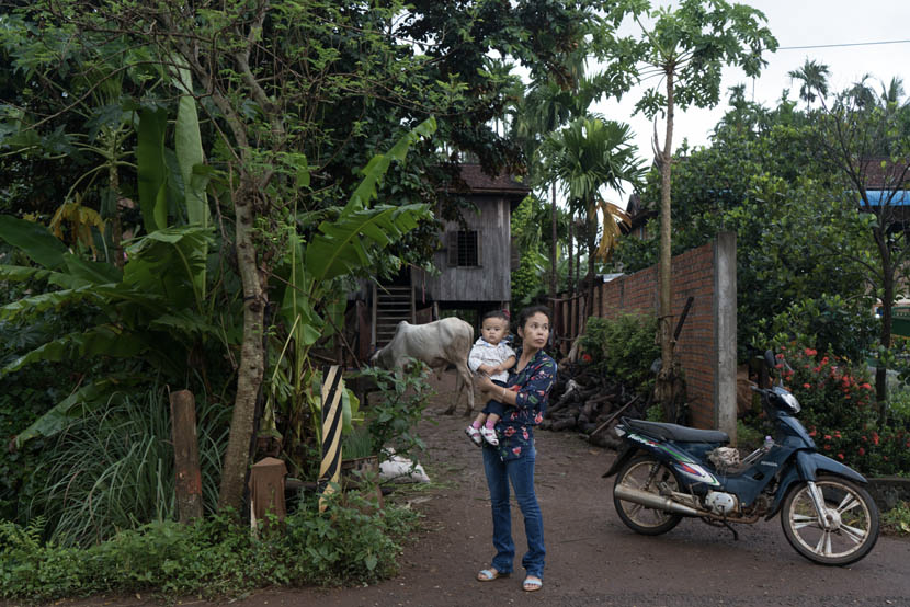 2017年9月，柬埔寨磅湛省，阿白在老家房门前抱着孩子。图/丛妍