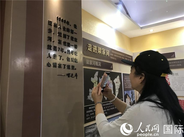在梁家河村史馆，留学人员代表正拍摄照片（徐祥丽 摄）