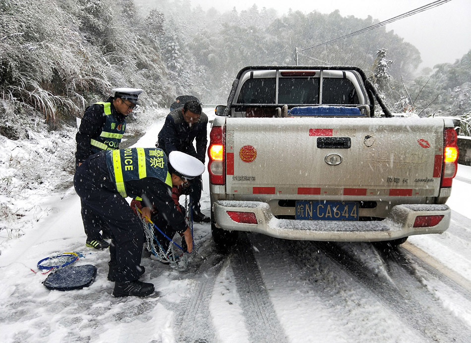 2018年12月7日凌晨，安徽省霍山县，今冬初雪如约而至，气温骤降。民警在冒雪帮助驾驶员安装防滑链