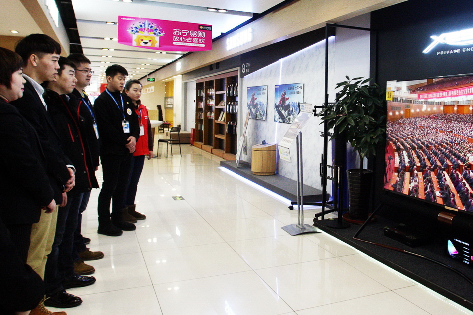 04-2018年12月18日上午，哈尔滨市道里区友谊附近一家商场内的电视机播放庆祝改革开放40周年大会的电视直播，商场员工和一些市民驻足观看。
