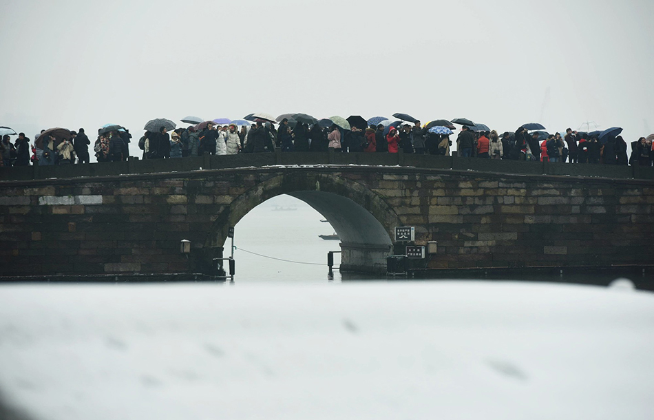 07-5479266174637179852018年12月9日，雪后杭州西湖断桥上是人头攒动。随着一夜降雪结束，雪后杭州西湖吸引了大批游客和市民前来，其中西湖断桥景点更是人潮汹涌，早就没了雪影，不少晚来游客戏称未见“残雪”只见“人桥”。