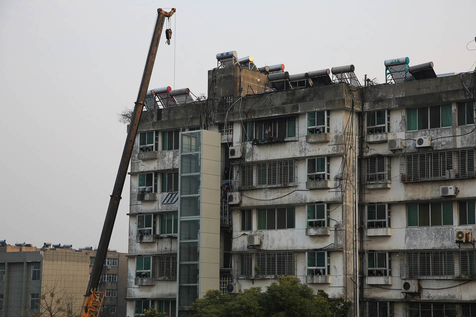 08-2019年1月1日，湖北省襄阳市，一个单位家属院的旧楼房在加装电梯，四个单元只有一个单元没有安装电梯。