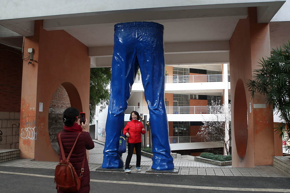 02-600668394966482959 2019年2月18日，重庆，某高校校园内一处“活在当下”网红雕塑，吸引众多游客“抱大腿”打卡拍照合影。