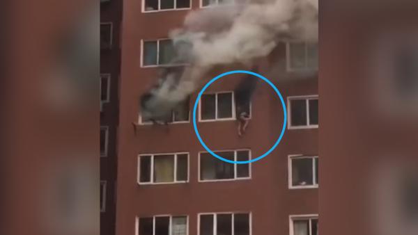 女子被火困窗沿即将跳下，消防一把救出
