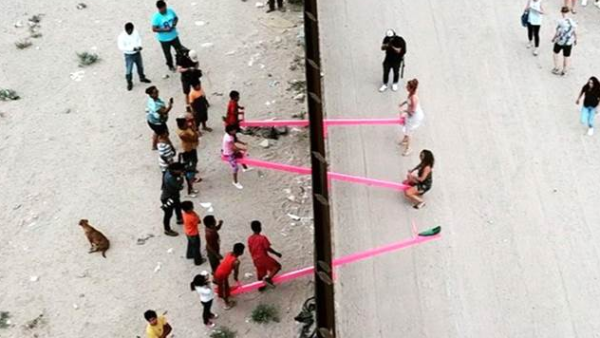 美墨边境粉色跷跷板，两国儿童隔墙玩耍