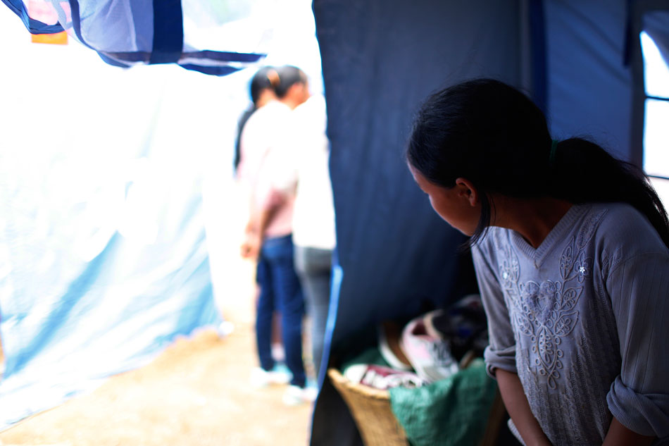 13.唐兴灿的妹妹在安置帐篷默默看着外面，帐篷外的人在谈论地震的遇难情况