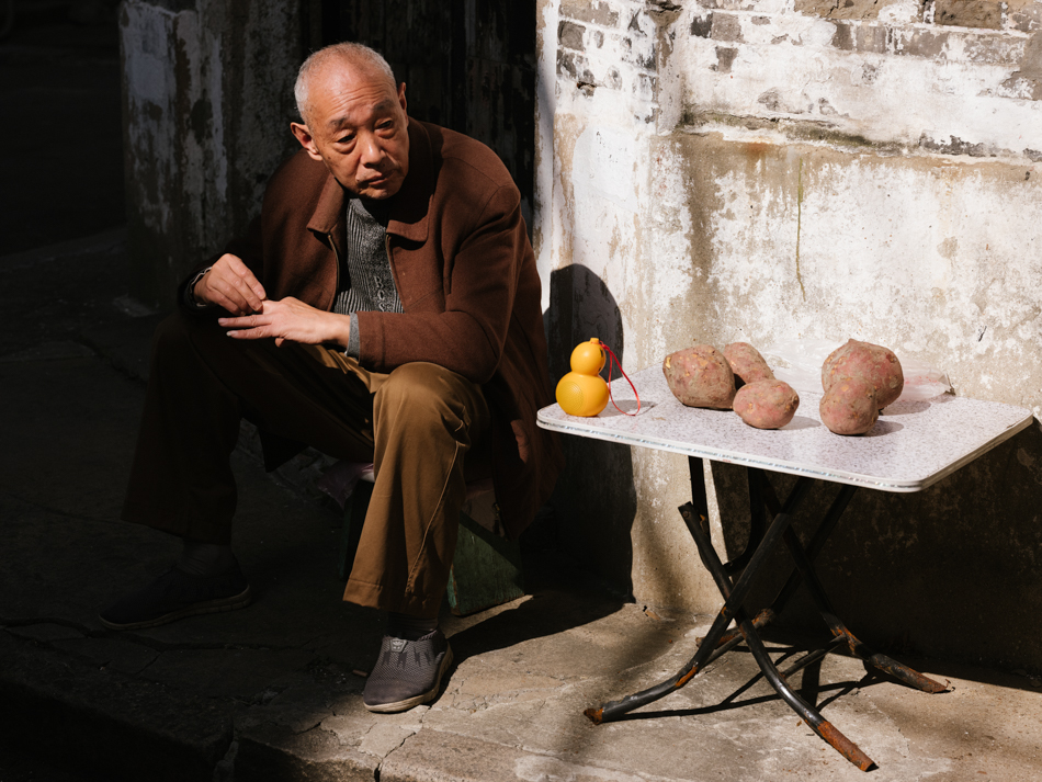 11-金家坊一位老人在晒太阳，一边收听桌子上葫芦形状收音机的节目