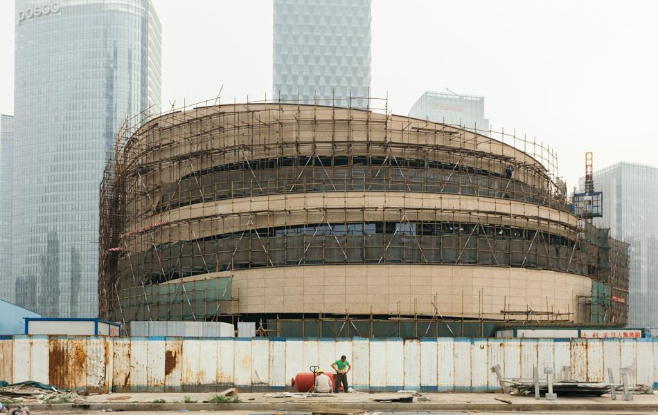 01 斗兽场 Colosseum  2016年，北京阿里巴巴大厦旁边一座建设中的环形建筑，两个建筑工人正在休息。其中一个撸起衣服露出肚皮，好似是罗马斗兽场里的勇士一样，面对着背后的这个庞然大物。_