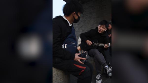 他背吉他在火车站唱歌：为回家的人送温暖