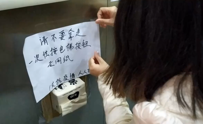 她在電梯內粘抽紙，方便鄰居無接觸按電梯