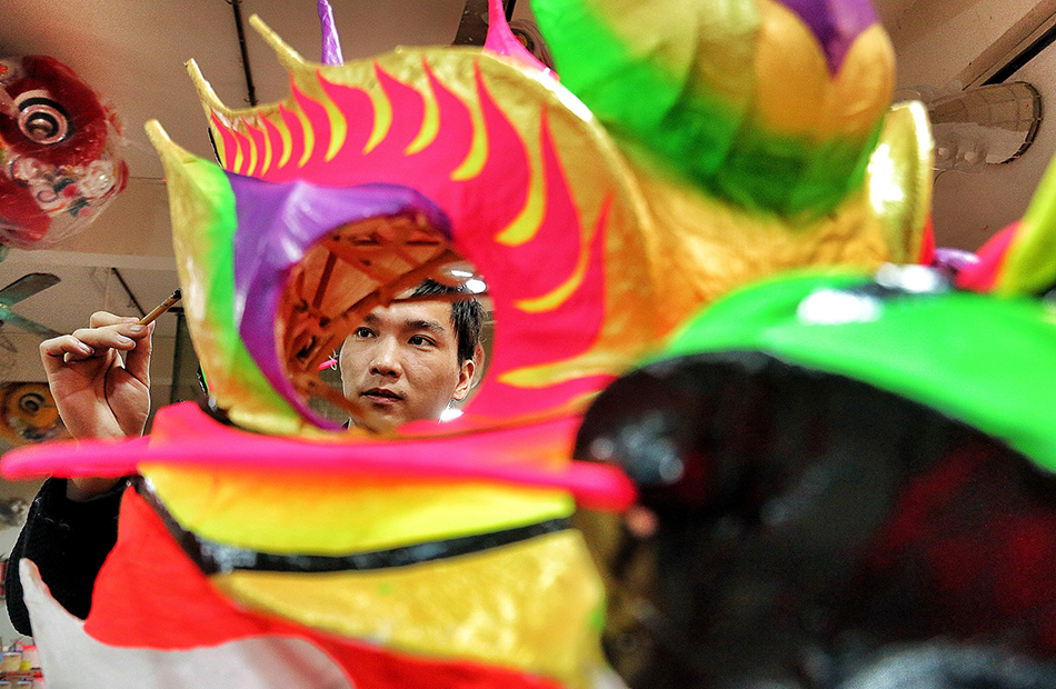 11.2014年12月4日，广东广州，描色工人发挥创作才华的时刻，画笔蘸上鲜亮的颜料，在狮头上描绘出千变万化的花色。图为一位描色工人为龙头上色。
