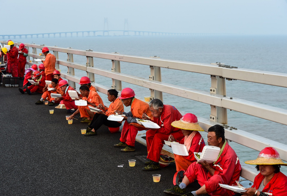 8.为了抓住大桥建设的天气窗口期，正在港珠澳大桥九洲航道桥面铺设沥青的工人们轮流吃晚饭（4月29日摄）。