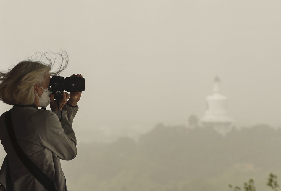 7.5月4日，在北京景山公园的万春亭，一名外国游客戴着口罩拍照。