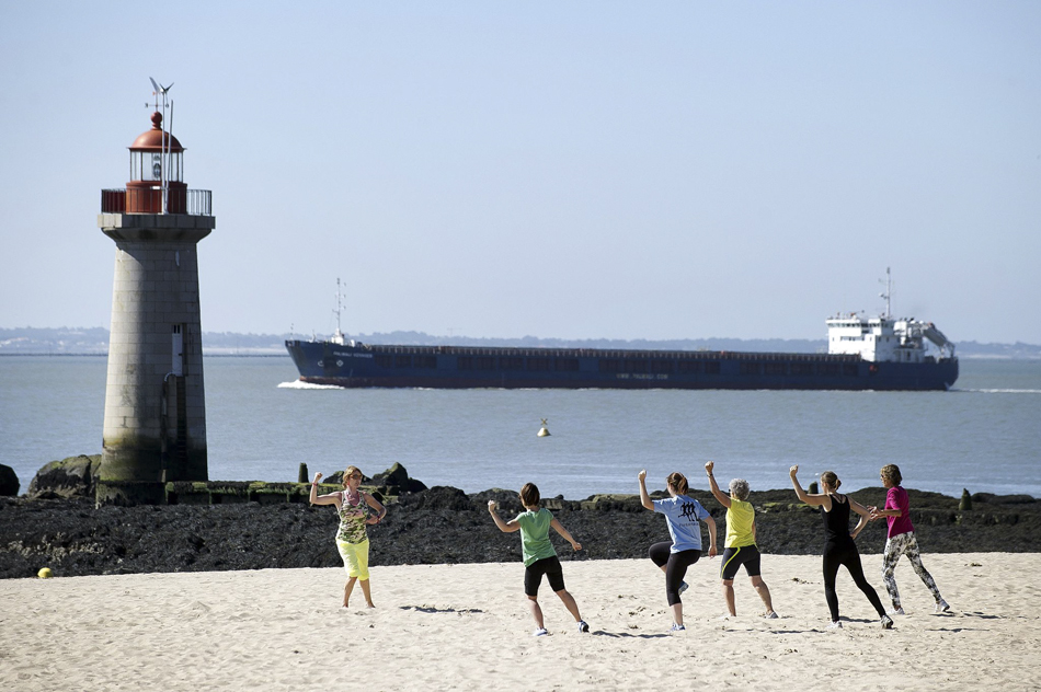 14.当地时间2014年7月10日，法国圣纳泽尔，民众在海滩上练习太极。