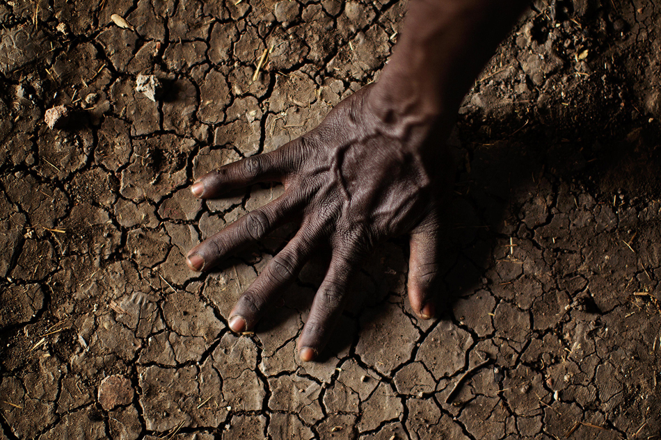 6.当地时间2012年4月8日，南苏丹尼罗河上游地区，一名男子将手放在干旱的土地上。