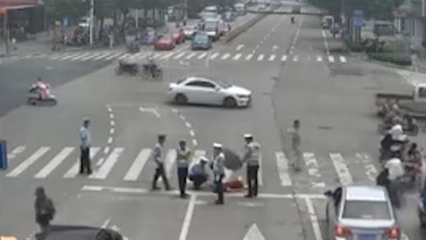 女子发病倒在车流中，交警施救遮伞保护