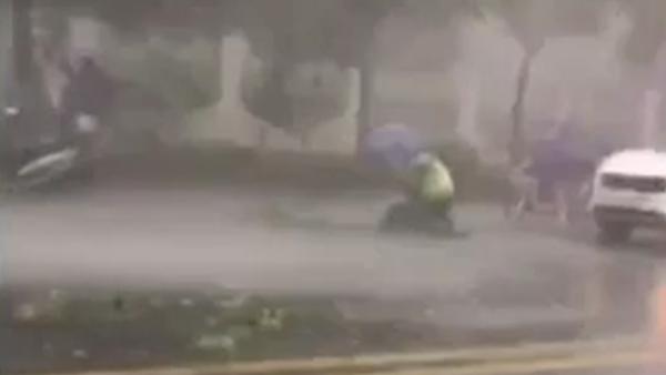 男子滑倒在车流中，交警施救遮伞保护
