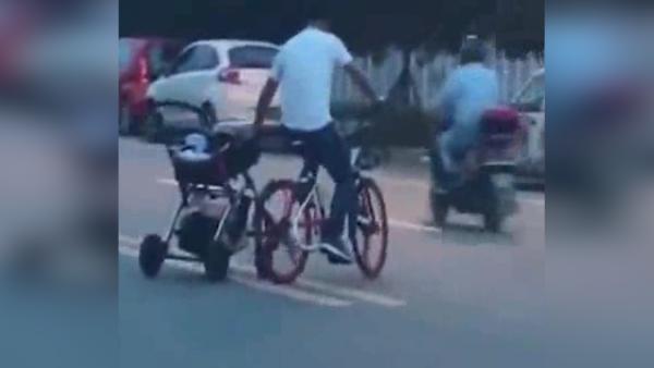 男子边推婴儿车，边骑共享单车横穿马路
