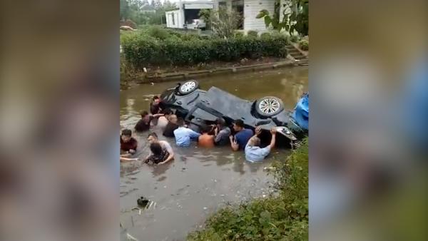 轿车被撞翻入河道，众村民跳水砸车救人