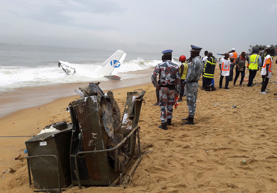 Policemen and rescuers stand near the wreckage of a propeller-engine cargo plane after it crashed in the sea near the international airport in Ivory Coast's main city, Abidjan, October 14, 2017