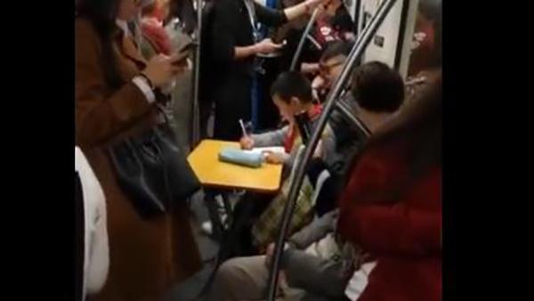 上海一学生自备折叠桌在地铁里写作业