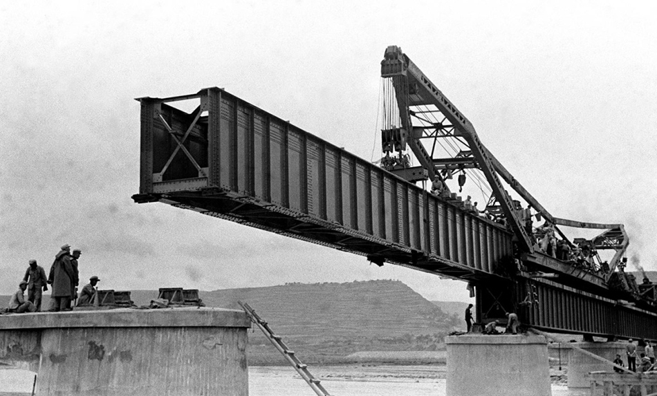 1954年，工人在宝成铁路渭河大桥工地架设钢板梁（资料照片）。