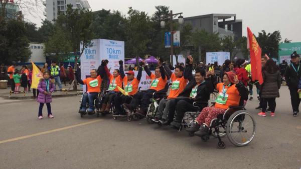残疾人坐轮椅“跑”马拉松，路人推上坡