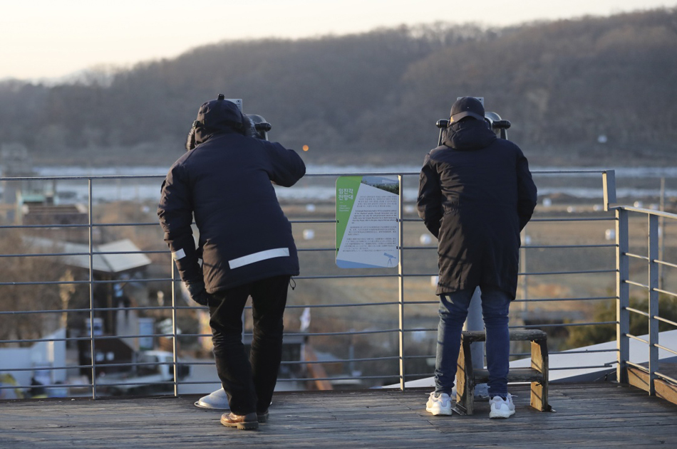 09-08-1月3日，在韩国北部的坡州，游客用望远镜向朝鲜方向眺望。