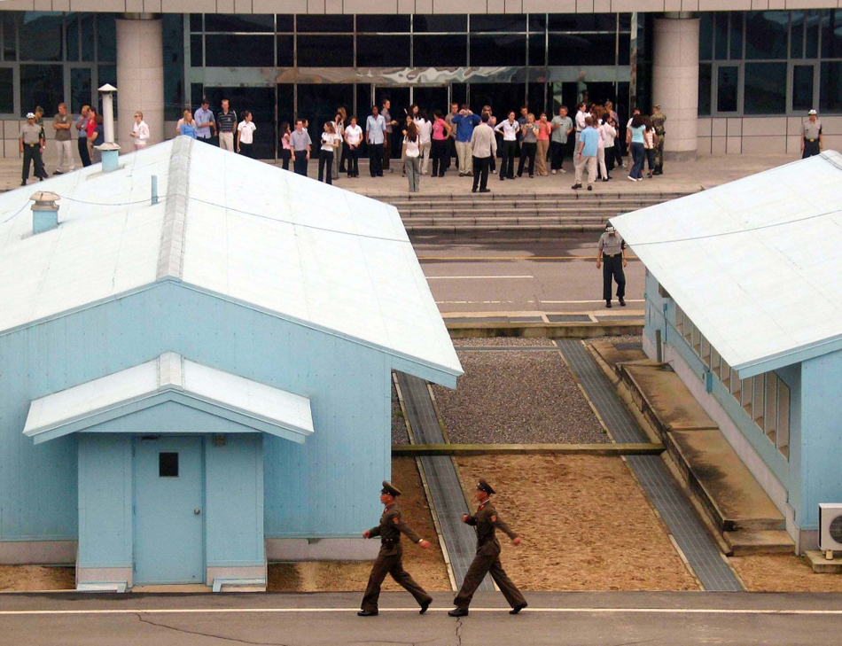 12-13-2004年7月26日拍摄的资料照片显示，来自世界各国的游客在板门店韩国一侧（上）参观，画面下部为板门店朝鲜一侧两名正在执勤的朝鲜人民军士兵。