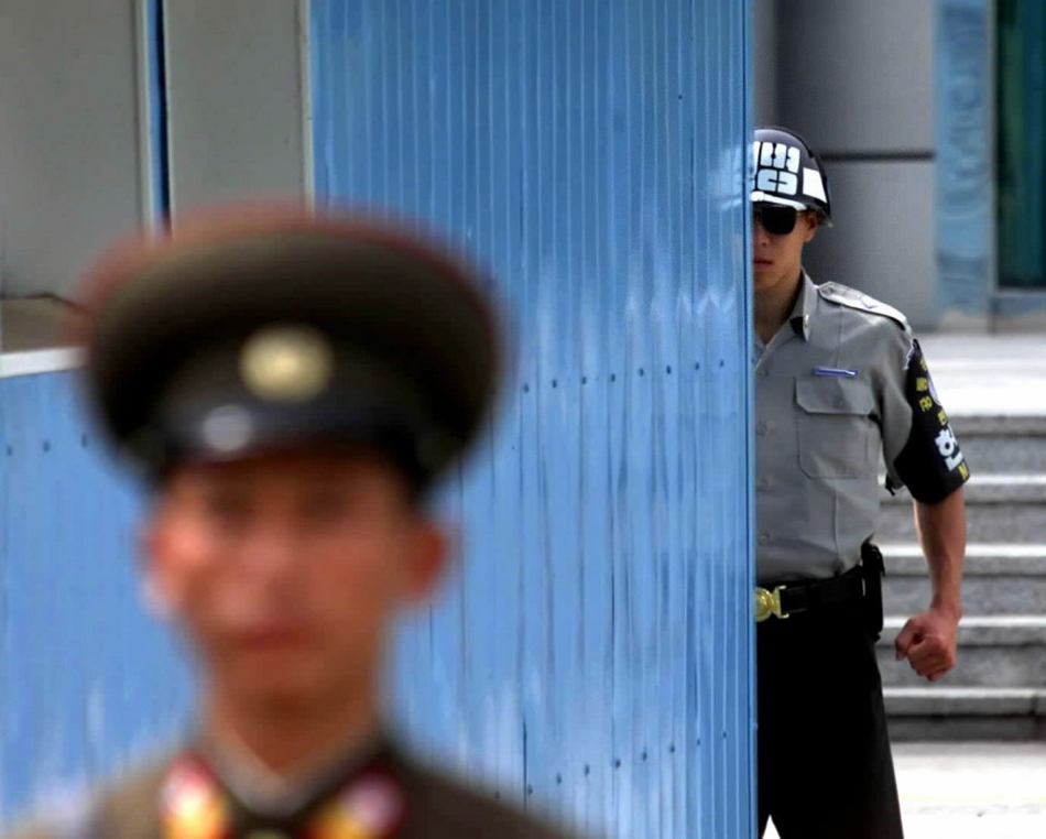 13-14-2002年9月19日拍摄的资料照片显示，一名韩国宪兵（右）和一名朝鲜人民军士兵在板门店朝鲜半岛军事分界线两侧执勤。
