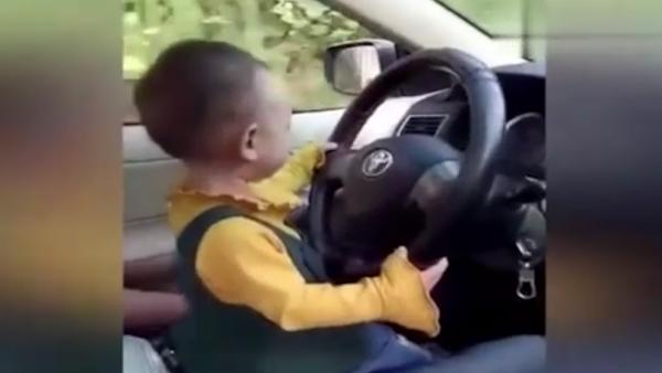 1岁女童坐父亲腿开车，母亲在旁笑出声